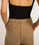 Pantalón wide leg color beige, de corte sastrero, con pliegues delanteros y cinturón.