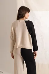 Sweater tejido color crema con mangas ranglán color beige y cuello redondo.