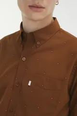 Camisa marrón con pequeños lunares rojos, de corte recto, manga larga y bolsillo en el pecho.
