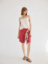 Bermuda color ladrillo de lino, tiro medio, con bolsillos laterales y pañuelo estampado atado a la cintura.