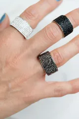 Anillo ancho de acero quirúrgico plateado con banda de cristales gris oscuro tipo pavé.