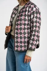 Campera acolchada color verde militar, con cuello redondo y cierre frontal de broches a presión. Presenta un patrón de costuras onduladas.