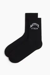 Pack de cinco pares de medias deportivas de caña media en punto fino suave de tejido funcional confeccionado con DryMove™, que ayuda a absorber el sudor y mantenerse frescos. Incluye un par negro, un par beige con una raya blanca, un par blanco con una raya gris, un par gris con dos rayas blancas y un par marrón con la inscripción "ACTIVE STHLM" en blanco.