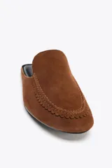 Zapato plano tipo babucha destalonada color marrón, confeccionada en serraje, con detalle de pespuntes en el cerco, copete subido y acabado en punta redonda.