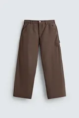 Pantalón negro de corte amplio, confeccionado en tejido de algodón con efecto lavado. Presenta bolsillos frontales, traseros de parche, tira multifunción y bolsillos laterales en las perneras. Cuenta con cierre frontal con cremallera y botón.