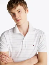 Chomba Tommy Hilfiger blanca con finas rayas horizontales celestes, corte regular, cuello clásico, tapeta de dos botones y logo bordado en el pecho.