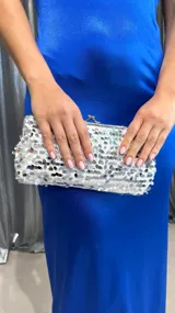 Cartera de mano plateada cubierta de lentejuelas, con cierre metálico y cadena plateada fina para colgar al hombro.