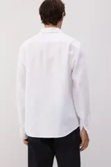 Camisa blanca de lino con cuello inglés, tapeta clásica y canesú en la espalda. Mangas largas con tapeta de manga y botón, y cierre ajustable de botón en los puños. Bajo redondeado. Corte estándar.