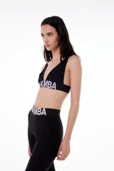 Corpiño deportivo negro de poliéster y elastano, con breteles finos y banda elástica bajo el busto con logo BLKMBA en blanco.