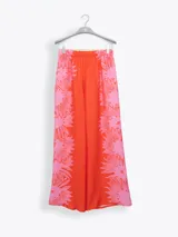 Pantalón palazzo color beige con estampado de girasoles marrones en el ruedo.