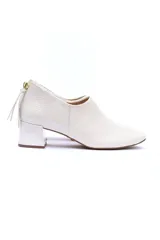 Zapato de cuero color blanco hueso, con punta cuadrada, suela laqueada antideslizante, cierre trasero y taco forrado de 5 cm.