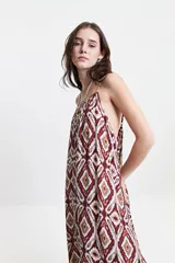 Vestido largo negro con estampado abstracto, de silueta amplia, con breteles finos y escote redondeado. Tiene un frunce sutil en el escote delantero y trasero que genera una caída fluida y relajada.