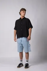 Camisa de lino negra de manga corta con cuello clásico y cierre frontal con botones.