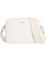 Bolso tipo cámara (camera bag) de Calvin Klein, color blanco, con cuerpo rectangular y esquinas redondeadas. Presenta un logo metálico plateado en el frente y una correa ancha de tela tejida con el nombre de la marca repetido.