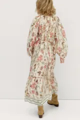 Vestido largo de viscosa con estampado floral, corte holgado, cuello redondo con botones y mangas globo largas. Incluye cinturón fino para atar.