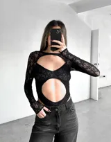 Body de encaje negro con mangas largas y aberturas en el pecho y abdomen.