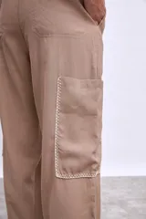 Pantalón cargo color beige con bolsillos laterales y bordados en hilo blanco en contorno de bolsillos y ruedo.