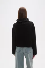 Buzo negro de manga larga con cuello alto tipo chimenea y un bolsillo cuadrado en el pecho.