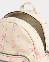 Mochila urbana negra de cuerina con bolsillo frontal con cierre y charm colgante de cadena con dije de corazón y candado. Tiene correas regulables, manija superior, cierre superior, doble bolsillo frontal (uno con charm metálico) y bolsillos laterales.