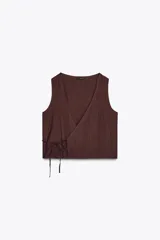 Top chaleco marrón con textura arrugada, escote en pico cruzado, sin mangas y cierre frontal cruzado con lazada lateral.