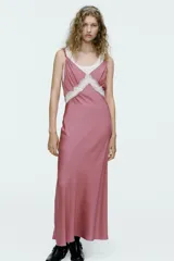 Vestido midi de satén color rosado, con escote en V, tirantes finos regulables y detalle de puntilla blanca en el escote.
