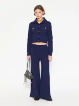 Pantalón azul de hilado frío, tejido cerrado y pesado, largo a los tobillos, con botones dorados en los laterales.