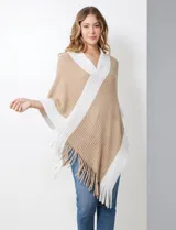 Poncho de tejido soft, color beige y blanco, con diseño cruzado en el frente y cuello en V. Presenta bordes y flecos en color blanco.