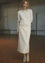 Falda midi color crudo de tejido bouclé con abertura en la parte posterior, tiro medio, goma elástica, cierre lateral y diseño recto.