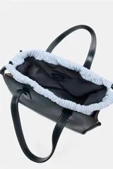 Bolso shopper azul marino con doble asa corta y correa larga de tela color crudo. Tiene detalle de pespuntes blancos y tira con anilla metálica.