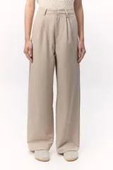 Pantalón sastrero de tiro alto color beige, con pierna ancha y pinzas que refuerzan la silueta moderna.