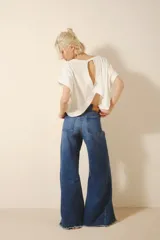 Pantalón jean corte oxford amplio de tiro medio, con cintura y cadera ajustada y piernas que se ensanchan desde la cadera hacia los tobillos con recortes en los laterales que le da un vuelo mayor a la pierna. Tejido rígido azul con lavado stone, localizado y bigotes. Con cierre y botón.