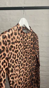 Top de microtul con estampado animal print de leopardo, cuello alto y mangas largas.