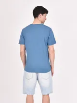 Remera gris con estampado rectangular con imágenes de paisajes y texto.