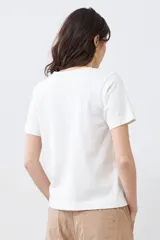 Remera color crudo de algodón, de corte recto y manga corta, con bordados calados en el escote.