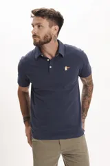 Chomba de piqué color marrón con cuello clásico y cierre de botones. Tiene un pequeño bordado de un pato en el pecho.