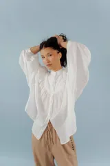 Camisa blanca de algodón con cuello mao, mangas largas abullonadas y costuras frontales.