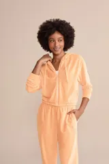 Campera cropped color durazno de tejido Frosty con superficie efecto plush y tacto ultrasuave. Tiene capucha con ajuste mediante amarre, cierre frontal con cremallera, bolsillos funcionales y recortes en las mangas.