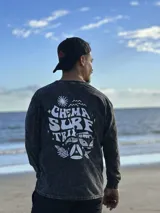 Buzo gris con efecto lavado, cuello redondo y puños acanalados. Estampado en el frente con la frase "Chema Surf Trip" y un dibujo de una camioneta combi.