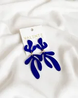 Par de aros colgantes de acrílico azul con diseño abstracto.