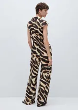 Mono largo de viscosa con estampado animal print en tonos marrones y beige. Tiene cuello camisero, cierre frontal con botones ocultos, cintura elastizada, bolsillos delanteros y diseño sin mangas.