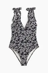 Traje de baño enterizo negro con estampado floral blanco, escote en V y breteles con moños.