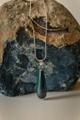 Collar dorado con cadena fina y dije colgante en forma de lágrima de piedra natural azul con vetas blancas.