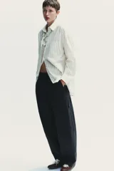 Pantalón cargo negro de corte amplio con cintura ajustable con cordón, bolsillos laterales y bolsillos tipo parche en las piernas.