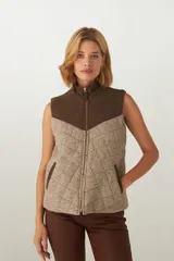 Chaleco corto de lana color marrón con diseño acolchado en forma de rombos. Presenta cuello alto, cierre frontal con cremallera dorada, dos bolsillos laterales y canesú en color marrón oscuro. Hecho en Uruguay.