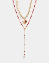 Set de dos collares dorados: uno con cadena de eslabones gruesos y dije de corazón esmaltado en rojo, y otro con cadena de cuentas rojas y dije de strass.