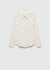 Camisa de manga larga color crema con estampado de lunares negros, cuello camisero y cierre frontal con botones.