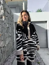 Buzo negro con estampado de cebra en blanco, con cuello alto y cierre parcial con botones a presión.