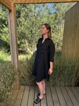 Vestido camisero blanco de lino, con cuello camisero, manga larga con botón para recoger, cierre frontal con botones de nácar, bolsillo en el pecho y diseño asimétrico más largo en la parte trasera.