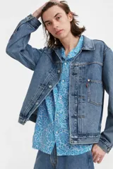 Campera de jean celeste de corte clásico con cuello camisero, cierre frontal con botones metálicos, bolsillos con solapa abotonada en el pecho y bolsillos laterales.