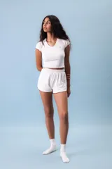 Conjunto de pijama color beige, compuesto por un top de mangas cortas con ribete marrón y shorts con ribete marrón.